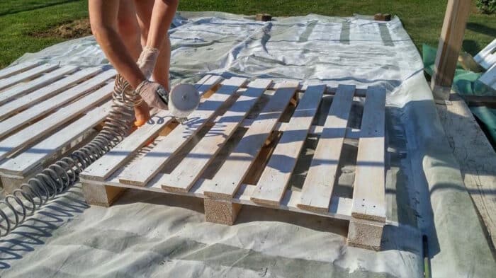 person painting wooden pallets