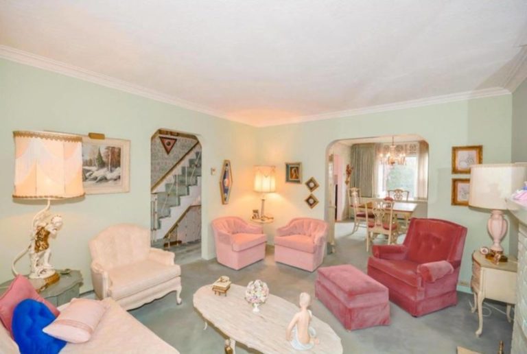 Sala de una casa con muebles rosados y rojos, con tres lámparas y cuadros en la pared