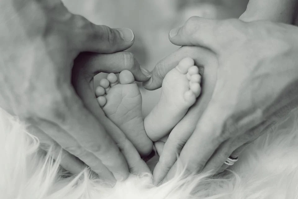 Manos de los padres tocando los pies de un bebé
